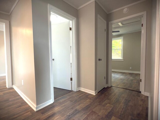 hall with dark wood-style floors, ornamental molding, and baseboards