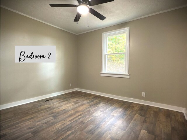 spare room featuring ornamental molding, dark wood finished floors, a textured ceiling, and baseboards