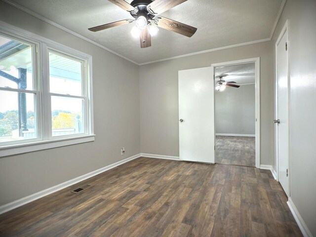 unfurnished room with baseboards, visible vents, dark wood-style flooring, and ornamental molding