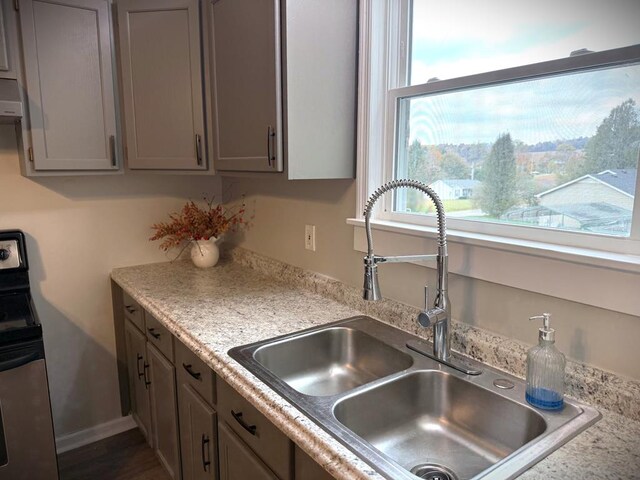 kitchen with extractor fan, gray cabinetry, a sink, baseboards, and stainless steel electric range