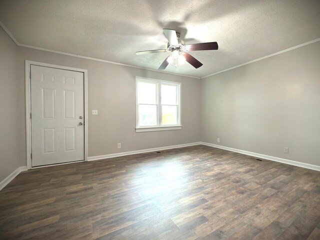 empty room featuring a textured ceiling, dark wood-type flooring, baseboards, and crown molding