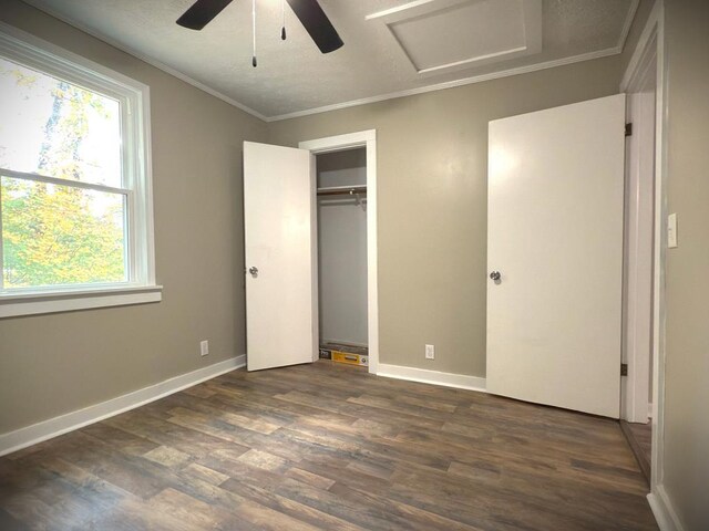 unfurnished bedroom featuring ornamental molding, dark wood finished floors, attic access, and baseboards