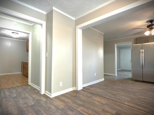 unfurnished room featuring crown molding, dark wood-type flooring, ceiling fan, a textured ceiling, and baseboards