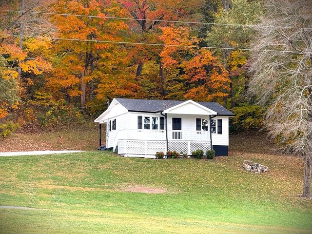 view of front of house featuring covered porch, a fire pit, and a front lawn