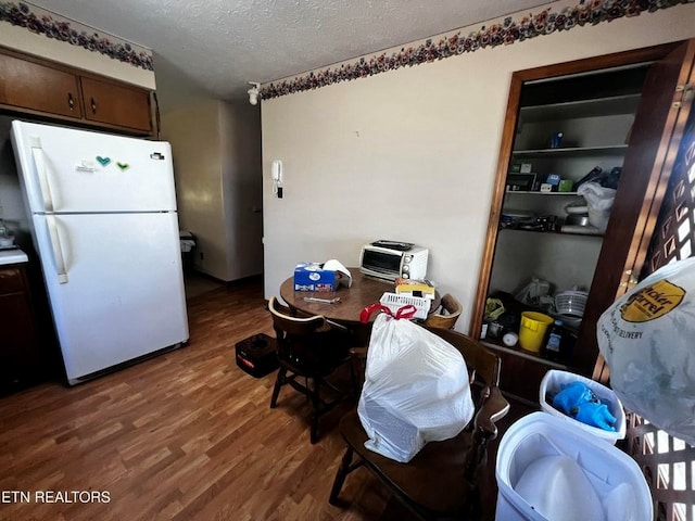 kitchen with a textured ceiling, wood finished floors, and freestanding refrigerator