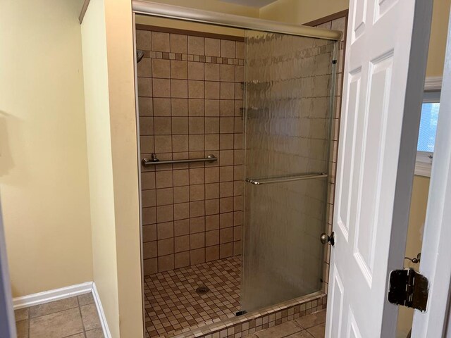 full bathroom featuring tiled shower, tile patterned flooring, and baseboards