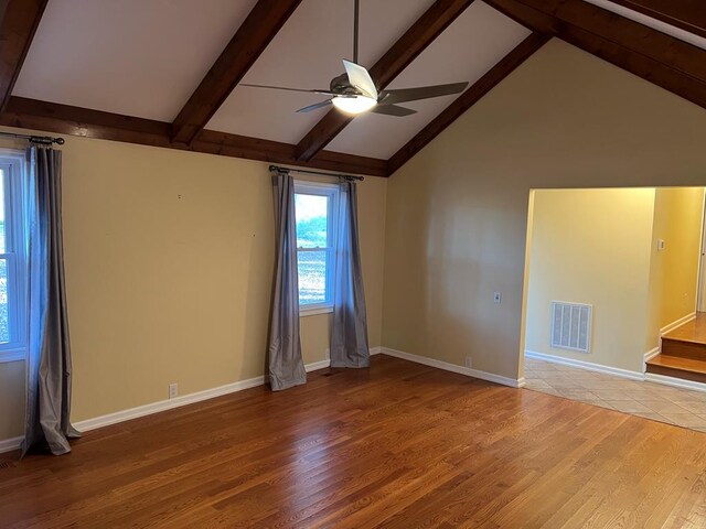 unfurnished room with wood finished floors, visible vents, baseboards, a ceiling fan, and beam ceiling