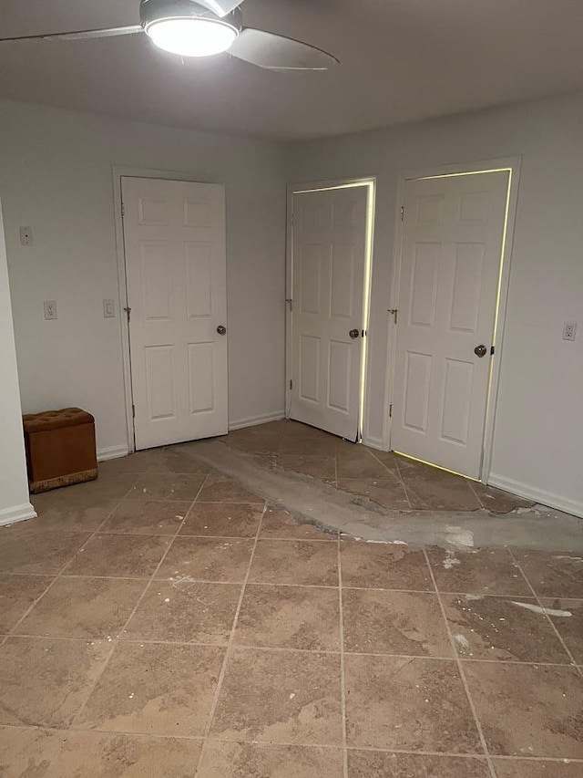 interior space featuring baseboards and a ceiling fan