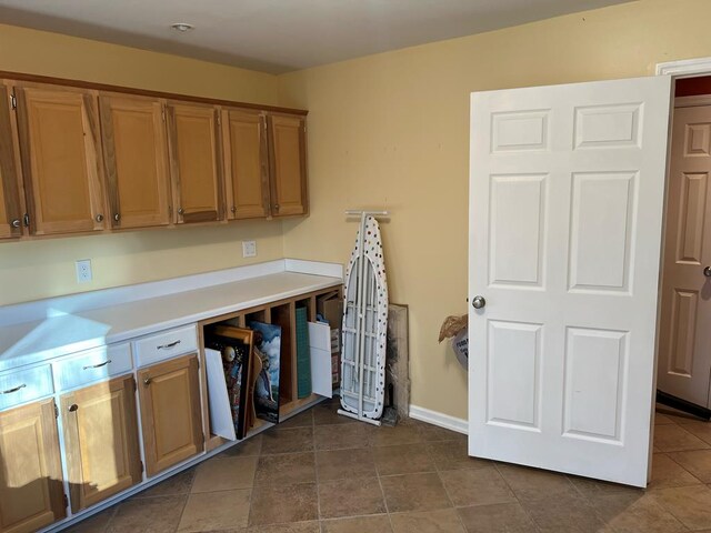 kitchen with brown cabinetry, light countertops, and baseboards