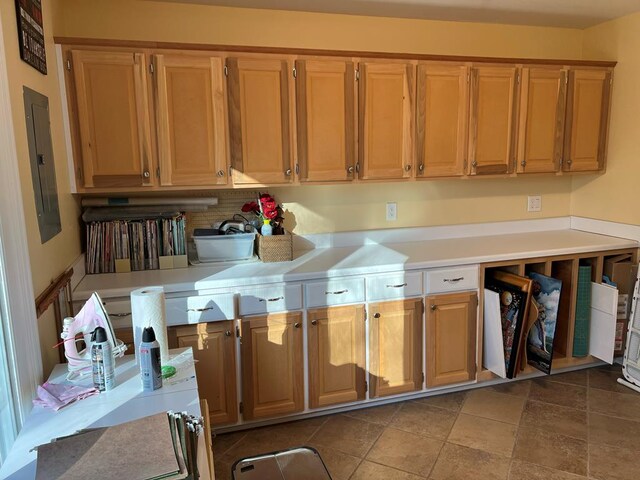 kitchen with light countertops, electric panel, and brown cabinets