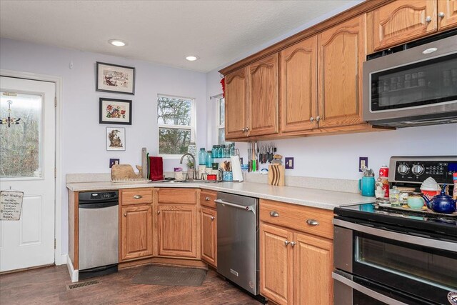 kitchen with recessed lighting, light countertops, appliances with stainless steel finishes, dark wood-type flooring, and a sink