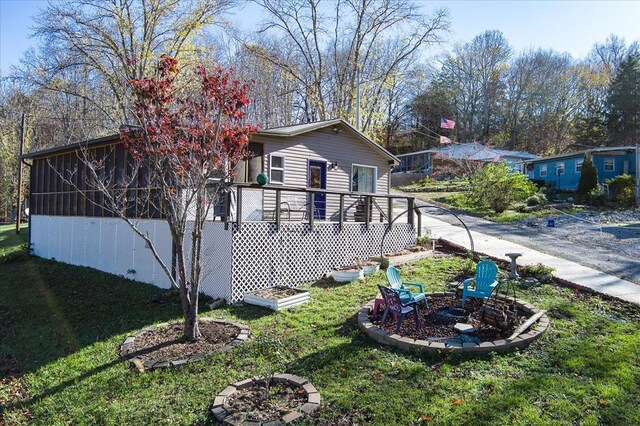 view of home's exterior with an outdoor fire pit, a sunroom, and a lawn