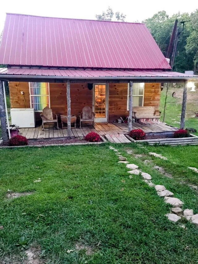 back of property with metal roof and a yard