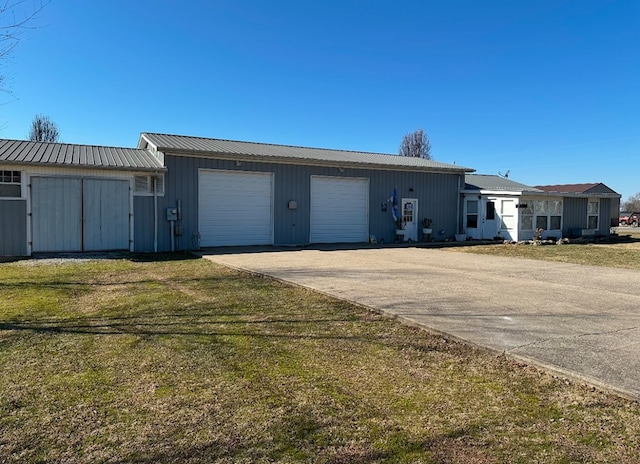 exterior space with driveway, a garage, metal roof, and a front yard