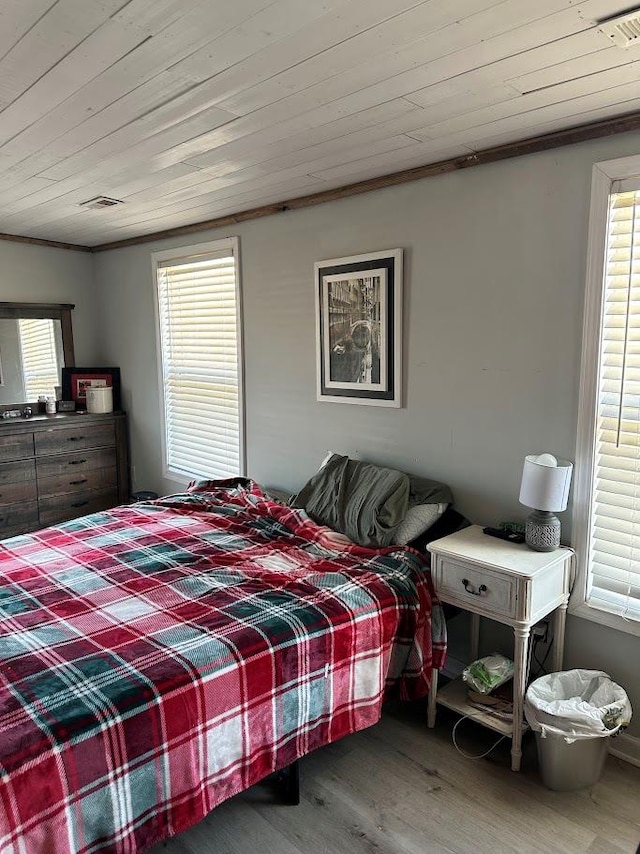 bedroom with wooden ceiling, visible vents, wood finished floors, and ornamental molding