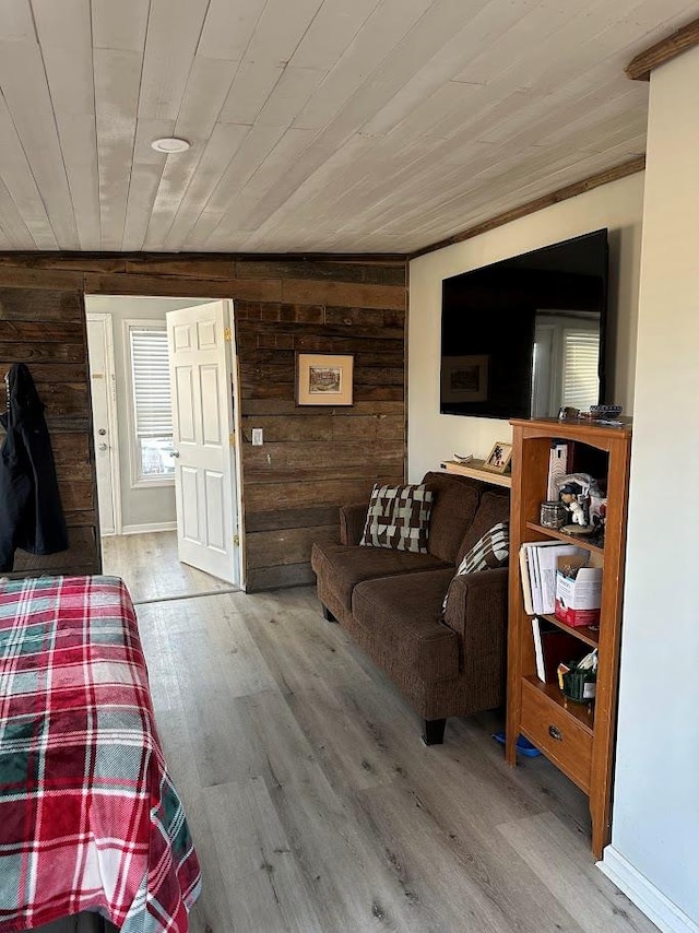 living area featuring light wood-type flooring, wooden ceiling, and wooden walls