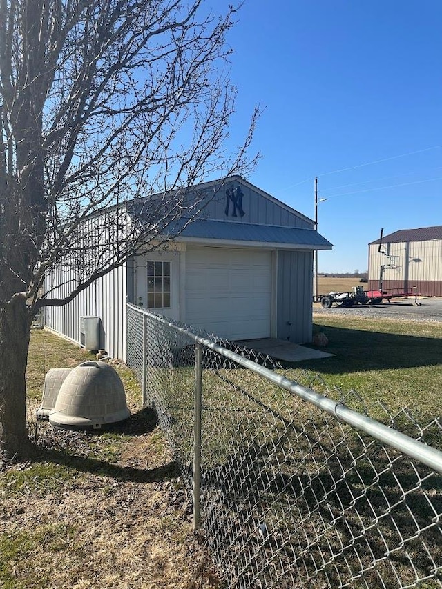 view of property exterior featuring a detached garage, fence, board and batten siding, and an outbuilding