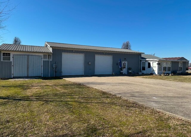 view of front of home featuring a garage, metal roof, concrete driveway, and a front yard