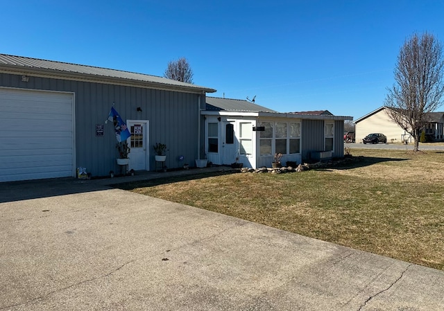 single story home with metal roof, a front lawn, board and batten siding, and an attached garage