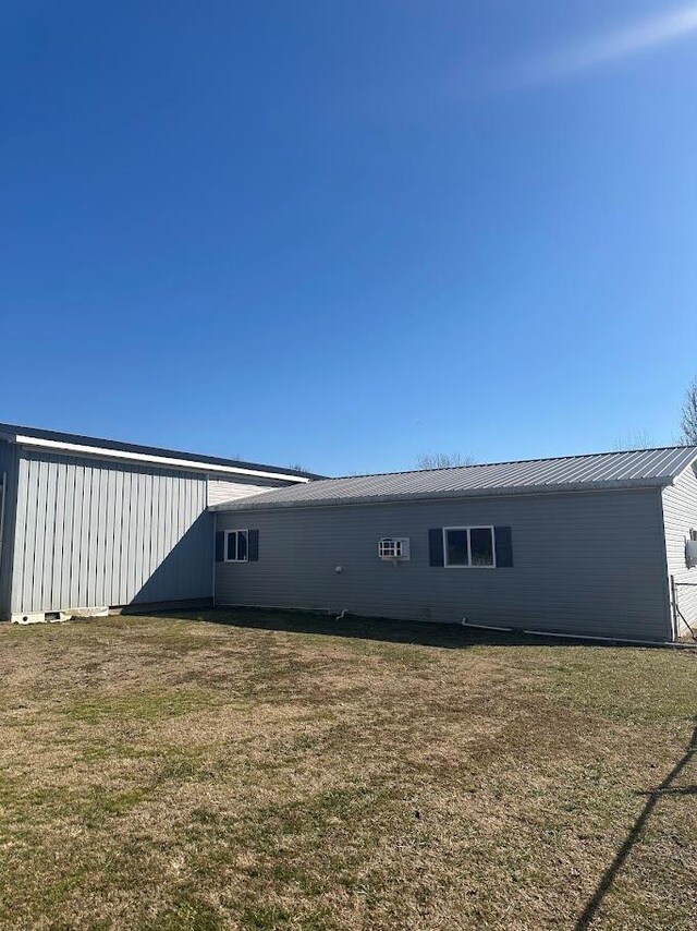 rear view of property featuring metal roof and a yard