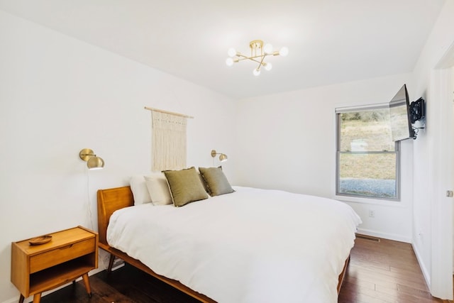 bedroom with hardwood / wood-style floors, a notable chandelier, and baseboards