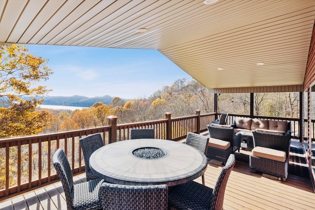 wooden terrace with outdoor dining space, outdoor lounge area, and a view of trees