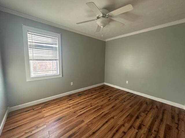 spare room featuring baseboards, wood finished floors, and crown molding