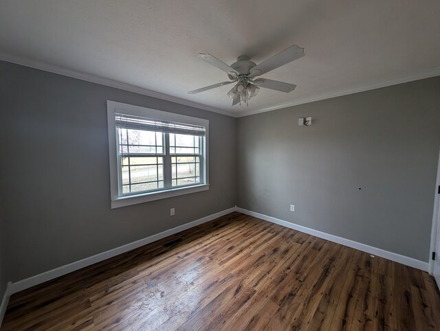 empty room featuring dark wood finished floors, crown molding, baseboards, and ceiling fan