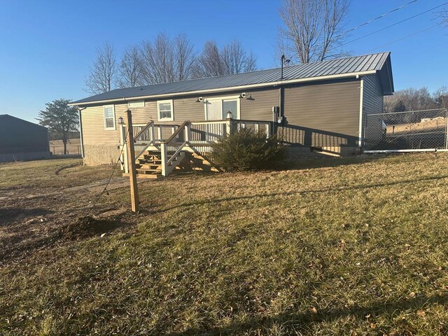 rear view of house with a yard, stairway, metal roof, fence, and a wooden deck