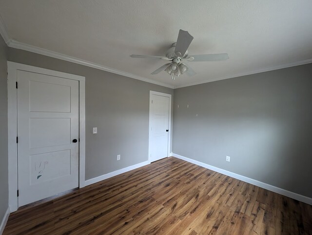 unfurnished bedroom featuring ornamental molding, dark wood finished floors, a ceiling fan, and baseboards