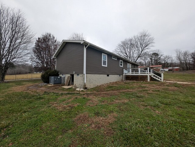 view of home's exterior featuring a deck, central AC unit, a lawn, and stairway