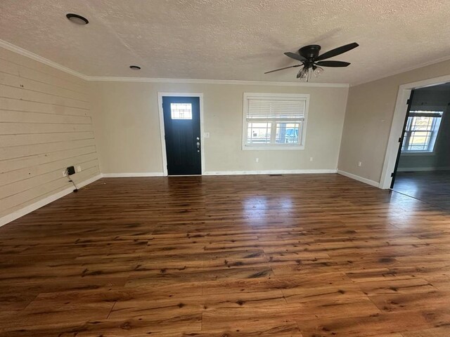 interior space featuring ornamental molding, dark wood-style flooring, wood walls, and a textured ceiling