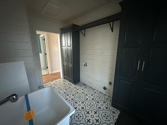 bathroom with a bathtub, tile patterned flooring, and wooden walls