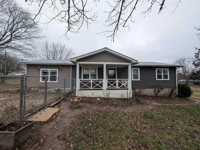 back of property with a porch, metal roof, and fence