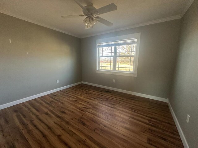 spare room featuring a ceiling fan, baseboards, dark wood-type flooring, and crown molding