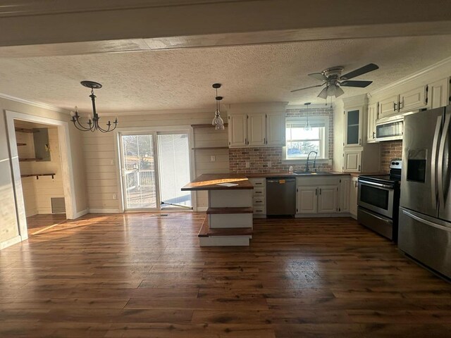 kitchen with dark wood-style flooring, stainless steel appliances, white cabinetry, pendant lighting, and a sink