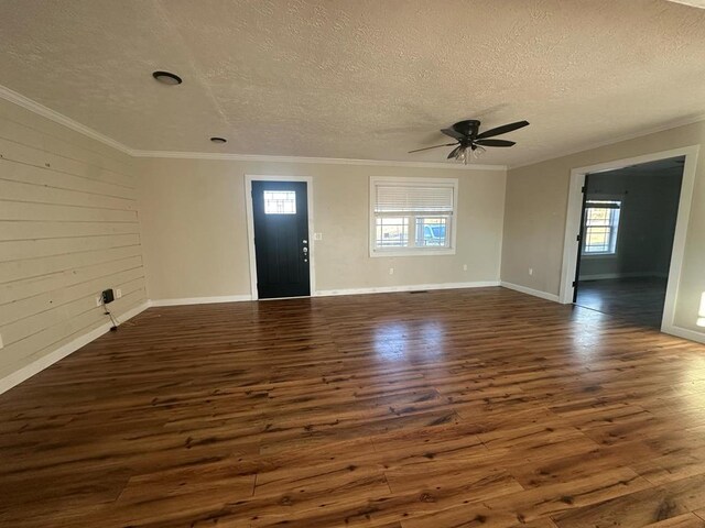 unfurnished living room with dark wood-style floors, ornamental molding, a textured ceiling, and ceiling fan