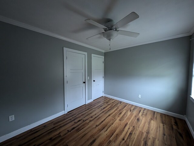 unfurnished bedroom featuring crown molding, baseboards, and wood finished floors