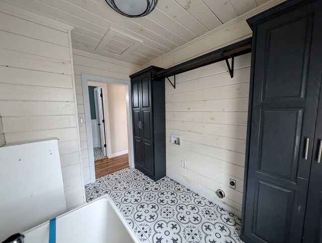 clothes washing area with wood ceiling, cabinet space, and wooden walls