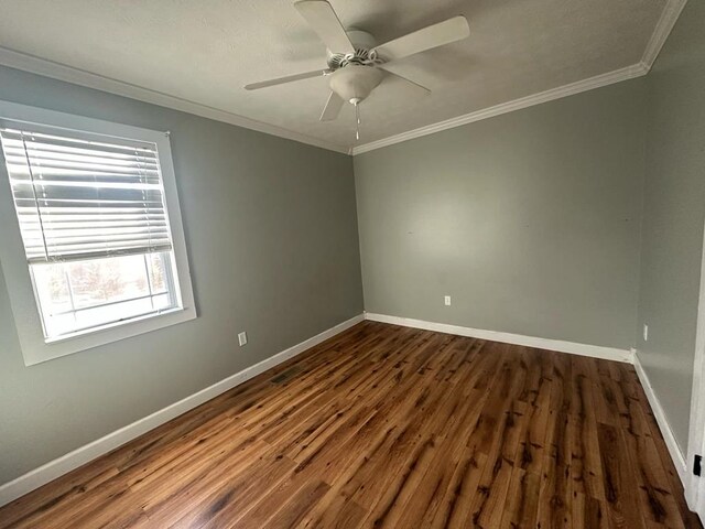 empty room with ornamental molding, dark wood finished floors, a ceiling fan, and baseboards