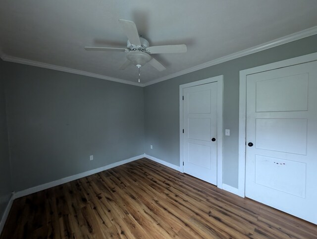 unfurnished bedroom featuring dark wood-type flooring, crown molding, baseboards, and ceiling fan