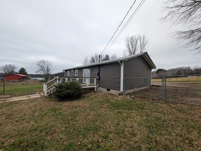 view of side of property with crawl space, a lawn, a deck, and fence