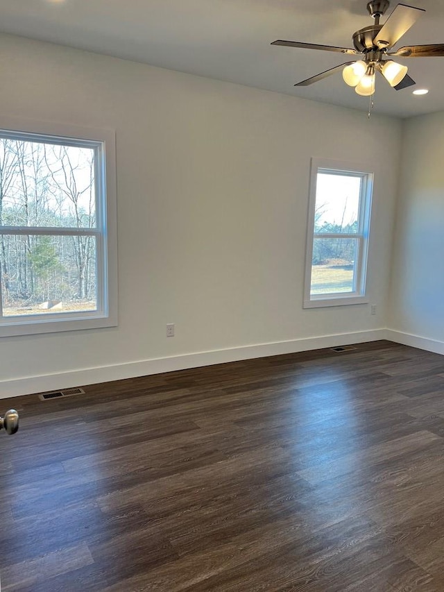 empty room featuring visible vents, dark wood finished floors, baseboards, and ceiling fan