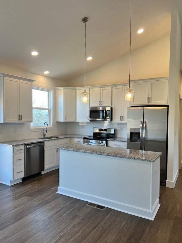 kitchen featuring appliances with stainless steel finishes, a center island, decorative light fixtures, white cabinetry, and a sink