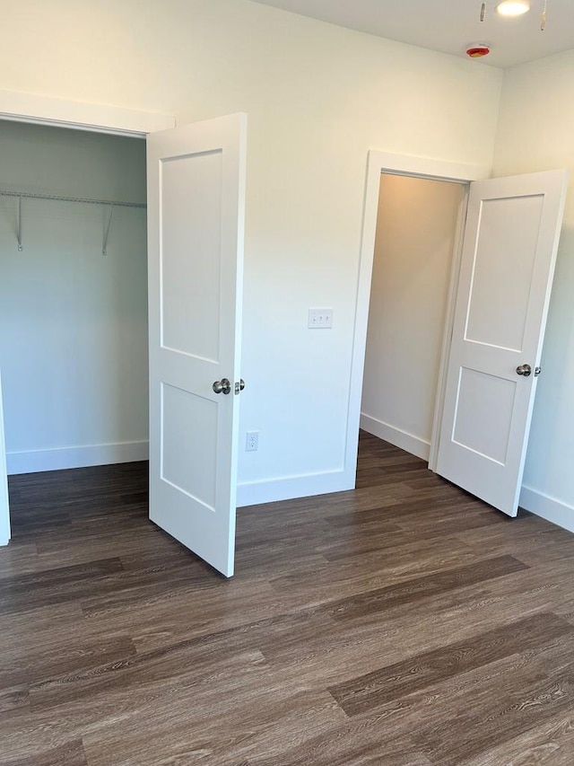 unfurnished bedroom with baseboards, dark wood finished floors, and a closet