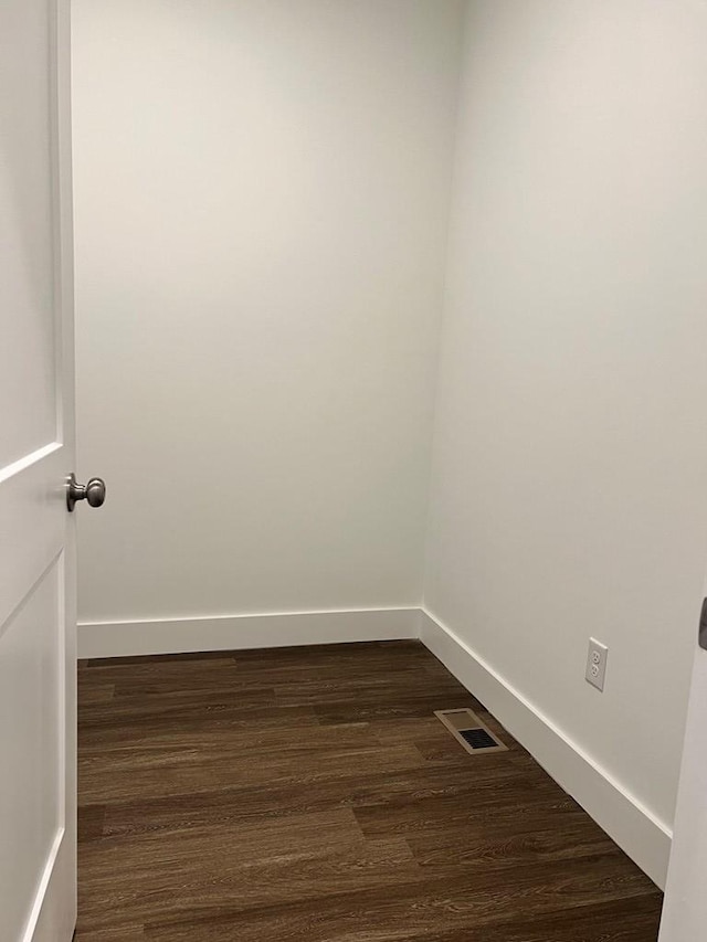 unfurnished room featuring dark wood-style floors, visible vents, and baseboards