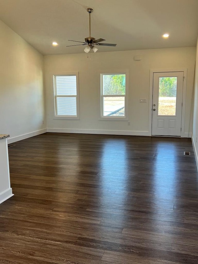 unfurnished living room featuring ceiling fan, baseboards, and dark wood-style flooring