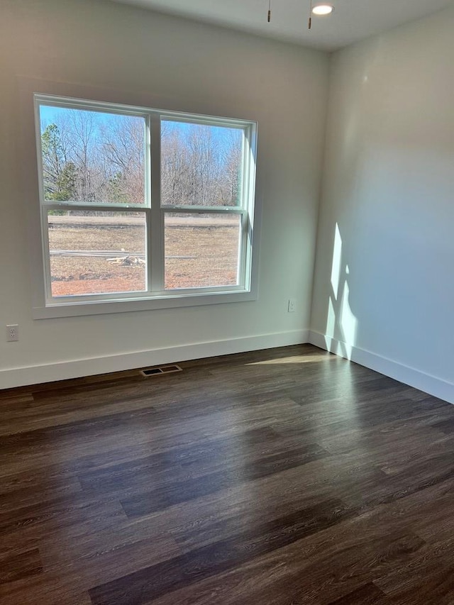 spare room with baseboards, visible vents, and dark wood-type flooring