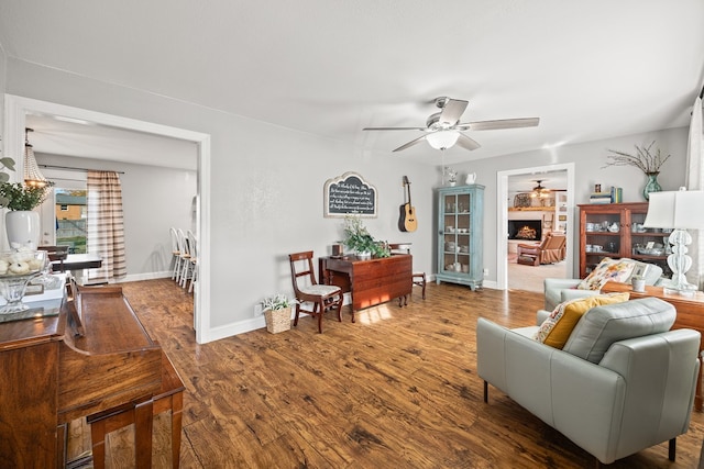 living room with built in features, wood finished floors, a ceiling fan, and baseboards