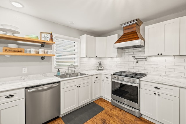 kitchen with stainless steel appliances, white cabinets, custom range hood, and a sink